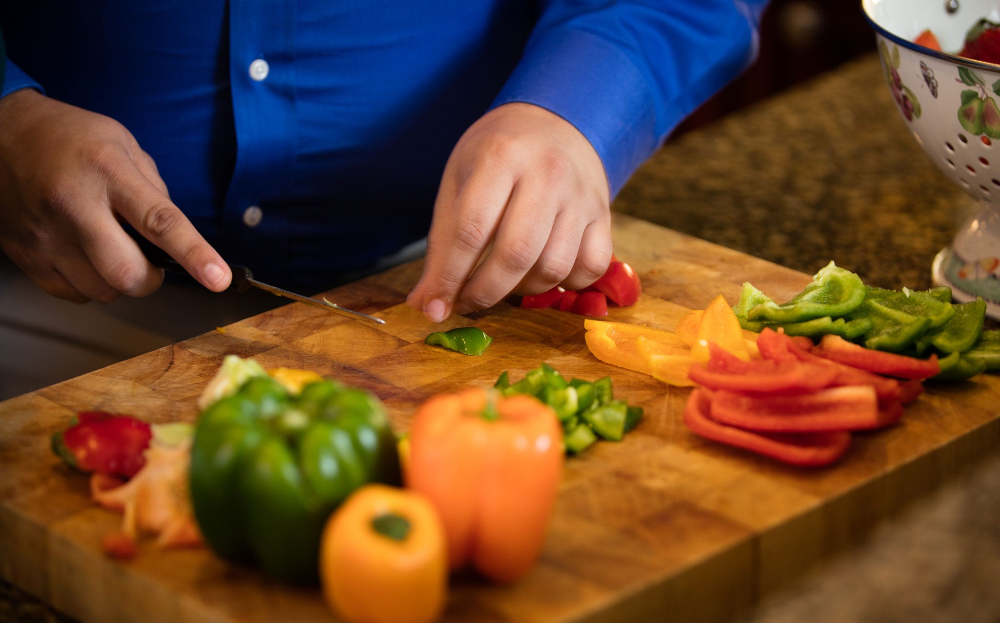 Hands cutting red, yellow, green peppers